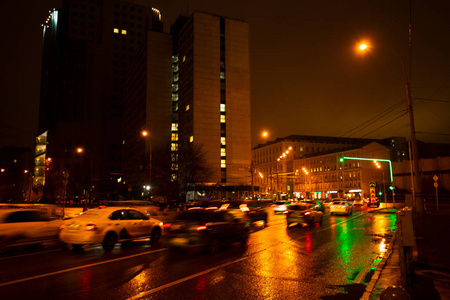 夜城在雨中发光。汽车在运动和模糊。户外照明