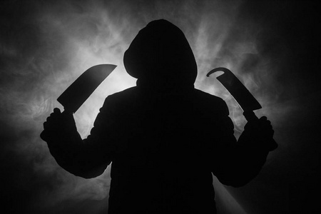 一个危险的头戴头套的人站在黑暗中拿着大刀.脸是看不见的.