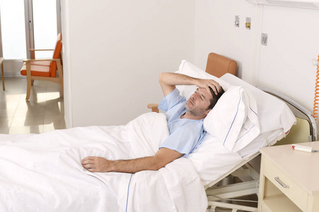 年轻有耐心的人躺在医院的床上休息累了看难过和沮丧，担心