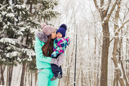 快乐妈妈和宝宝在冬季公园。在户外的家庭。性格开朗的妈妈和她的孩子