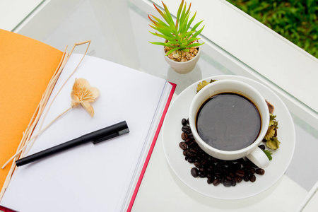 特写镜头黑咖啡在咖啡桌上与咖啡豆, 笔记本, 钢笔, 股票摄影师