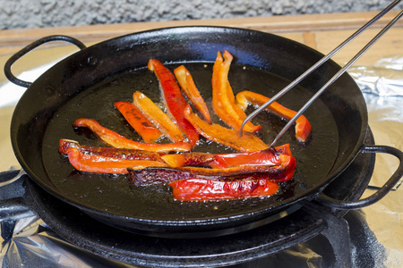 煎红辣椒片在平底锅和使用筷子