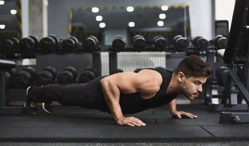 力量和动力。穿着运动服的男子在健身房做俯卧撑