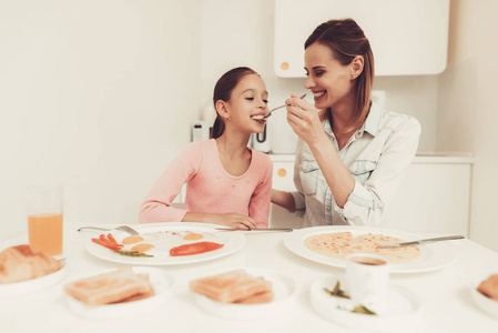 妈妈和女儿正在厨房吃饭.家庭关系的概念.早餐时玩得开心.