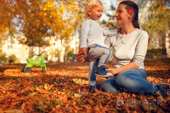 快乐家庭微笑的母亲和孩子男孩在秋天公园里玩耍和欢笑