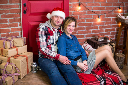 年轻快乐搞笑的家庭坐在圣诞节内饰和礼物的背景上