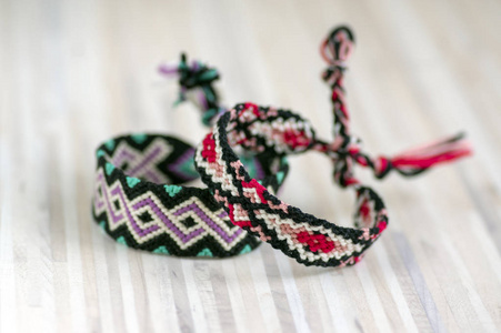 两个手工制作的自制五颜六色的自然编织手镯的友谊隔离在浅色木制背景, 鲜艳的色彩