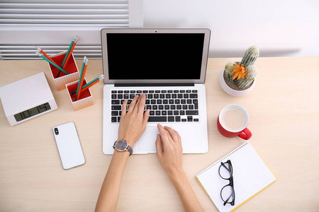 女性博客使用笔记本电脑在餐桌上, 顶部视图。用于样机的空白屏幕