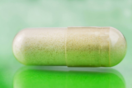 氨基葡萄糖胶囊食品补充丸对光泽的绿色背景，宏观图像