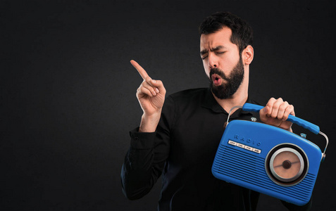 有胡子的英俊的人拿着收音机在黑色背景上