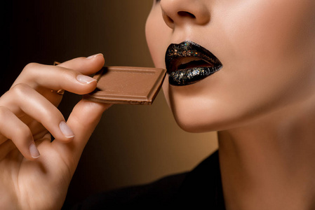 关闭女人的黑嘴唇和巧克力