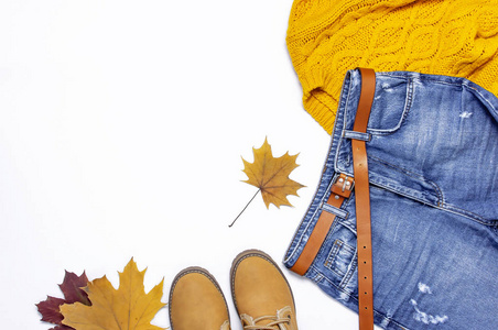 女性橙色针织毛衣, 蓝色牛仔裤, 靴子和秋叶白色背景上的顶层景观平躺式时尚女士服装集时尚舒适针织秋季配件女性时尚造型