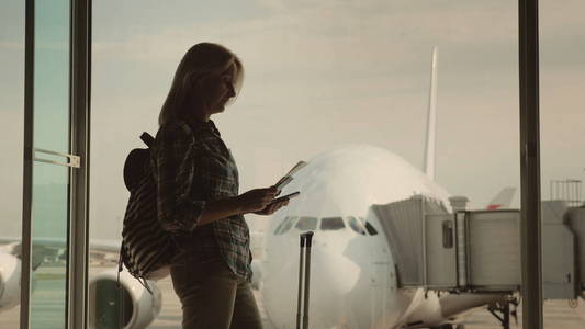 一个年轻的女人在等着登机。持有护照和登机牌。旅程的开始