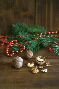 质朴的背景与核桃, 冷杉树枝和红色珠球圣诞装饰。您可以将其用于贺卡或优惠券。复制文本的空间。自然新年概念