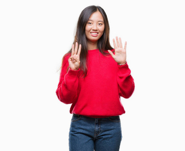年轻的亚洲妇女穿着冬季毛衣在孤立的背景显示和指向手指八, 而微笑着自信和快乐