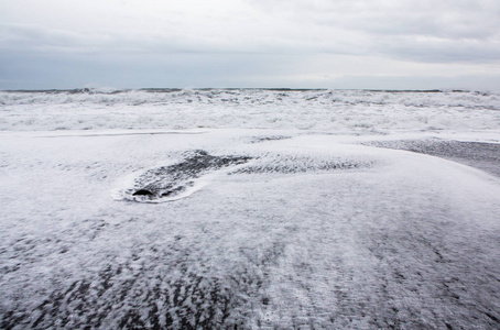 冰岛南部海岸的维克附近的黑色沙滩的形象。冰岛南部黑色熔岩海滩上的白色泡沫。冰岛的景点和自然风光