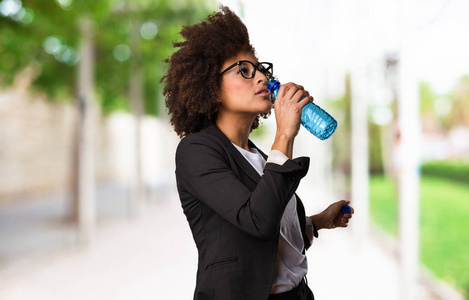 黑企业妇女饮水在模糊的背景图片