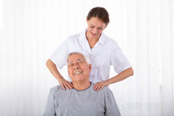 年轻的女性理疗师按摩老人的肩膀在临床