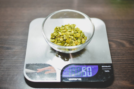 厨房称与五十克的绿色南瓜种子在厨房称重机在一个黑暗的木桌上的玻璃