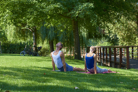 年轻女子和男子一起在户外练习瑜伽的全长镜头