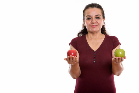 一个工作室拍摄的成熟波斯妇女拿着红苹果和绿色