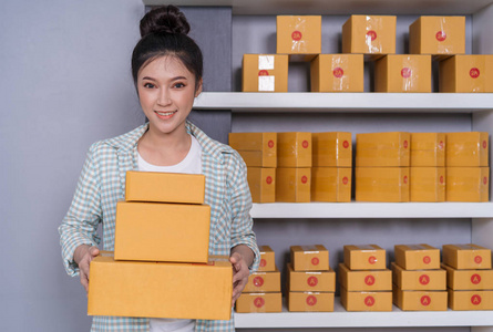 年轻的女企业家与包裹盒在她自己的工作购物网上企业在家里