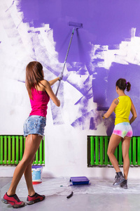 妇女涂料白墙与紫色油漆滚筒