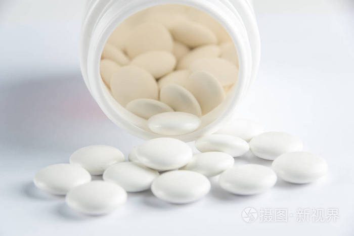 覆盖有盖的白色圆形片剂散落在塑料可以与他们