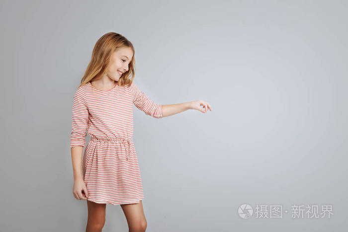 可爱小女孩微笑着站在孤立的灰色背景