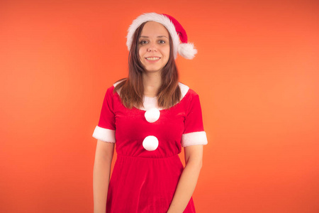 在橙色背景打扮成圣诞老人的年轻女孩的肖像。新年快乐, 圣诞快乐