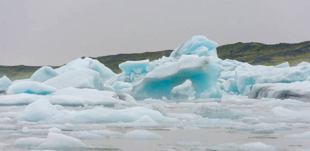 在南冰岛巨大的 Vatnajokull 冰川的手臂上的 Fjallsarlon 冰川泻湖上的小船游的蓝色冰