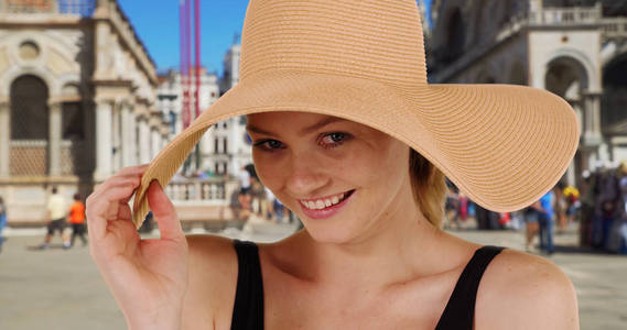 快乐时尚的白种人女孩在圣马克广场微笑着在相机