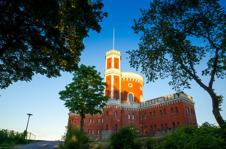 砖橙色城堡城堡 kastellet 与堡垒塔在 kastellholmen 海岛与绿色树在附近和蓝色清楚的天空背景, 斯德哥尔摩