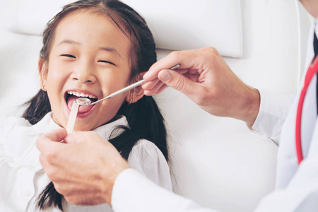 友好的年轻牙医检查在牙科诊所快乐的儿童牙齿。牙科概念