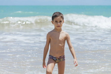 六岁的男孩在阳光明媚的日子，热带海滩上玩乐