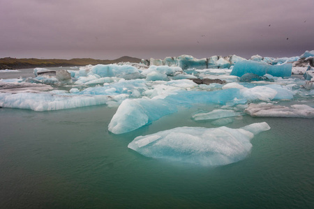 在南冰岛巨大的 Vatnajokull 冰川的手臂上著名的 Jokulsarlon 冰川泻湖上的蓝色冰