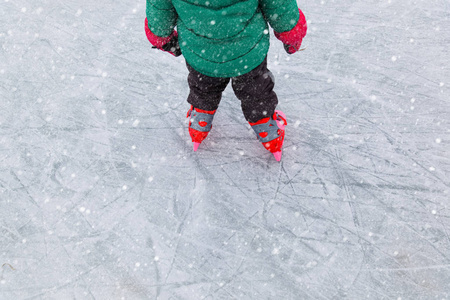 学习在冬天在冰上滑冰的小女孩