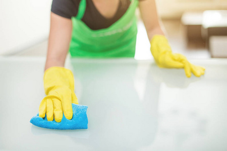 一个穿围裙的年轻女子用抹布擦灰尘照片