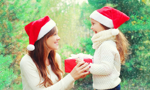 圣诞节家庭儿童和母亲在与框礼物的圣诞老人的红色帽子