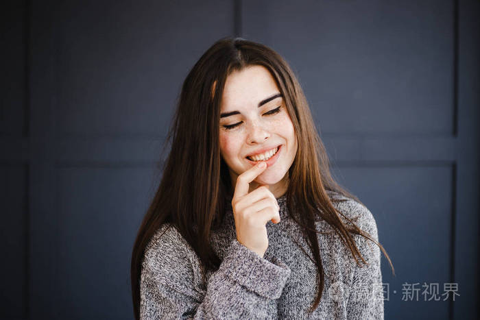 迷人的年轻女子带着狡猾的微笑把目光移开