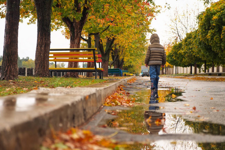 秋天, 孩子沿着堤防走过水坑。多云多雨天气