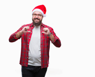 年轻的高加索男子戴着圣诞帽在孤立的背景看起来自信与微笑在脸上, 用手指指向自己骄傲和快乐
