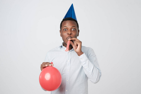 非洲年轻人在派对上玩得很开心, 穿着蓝色衬衫和节日帽, 吹响派对号角