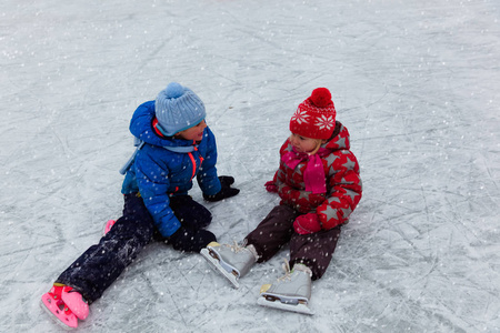 快乐的小的男孩和女孩一起滑冰