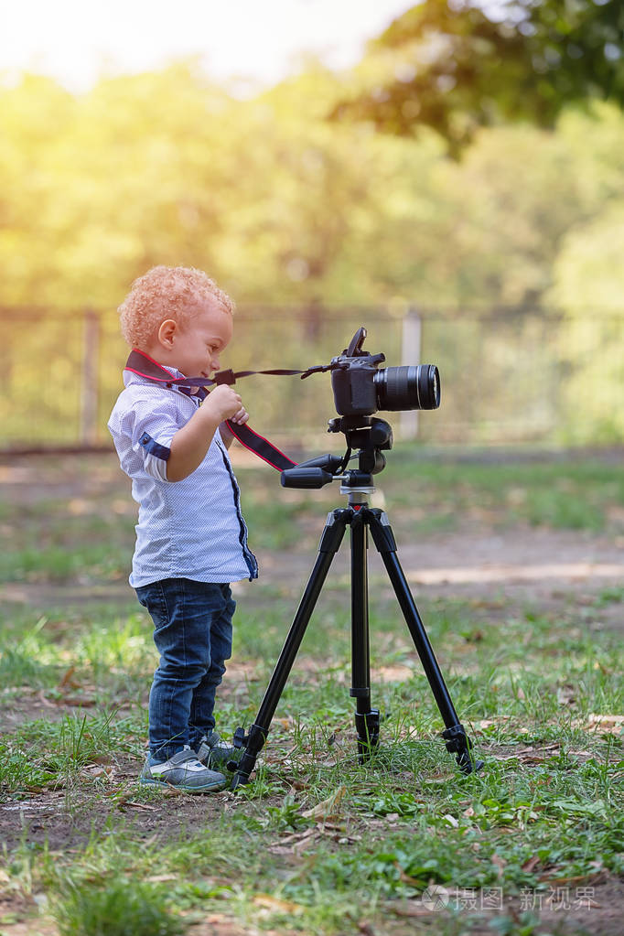 孩子拿着三脚架上的相机, 拍下风景.