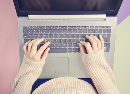 女孩在笔记本电脑键盘上打字。极简主义的趋势。在线工作, 自由职业者, 博客。在柔和的背景上的顶部视图