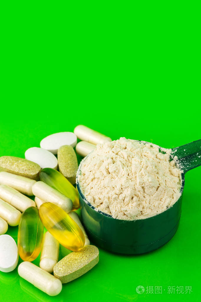 照片 混合的天然食品补充药片和蛋白粉在绿色背景上的塑料勺jpg