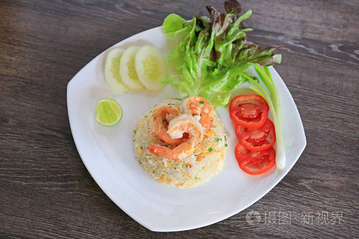 泰式炒饭配虾在白色的盘子对木桌。蔬菜食品装饰