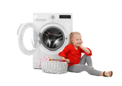 可爱的小女孩坐在篮子附近与洗衣房和洗衣机在白色背景