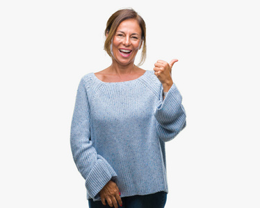 中年资深西班牙裔妇女穿着冬季毛衣在孤立的背景微笑着快乐的脸看着, 并指向侧面与拇指向上